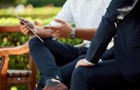 people on bench looking at iPad